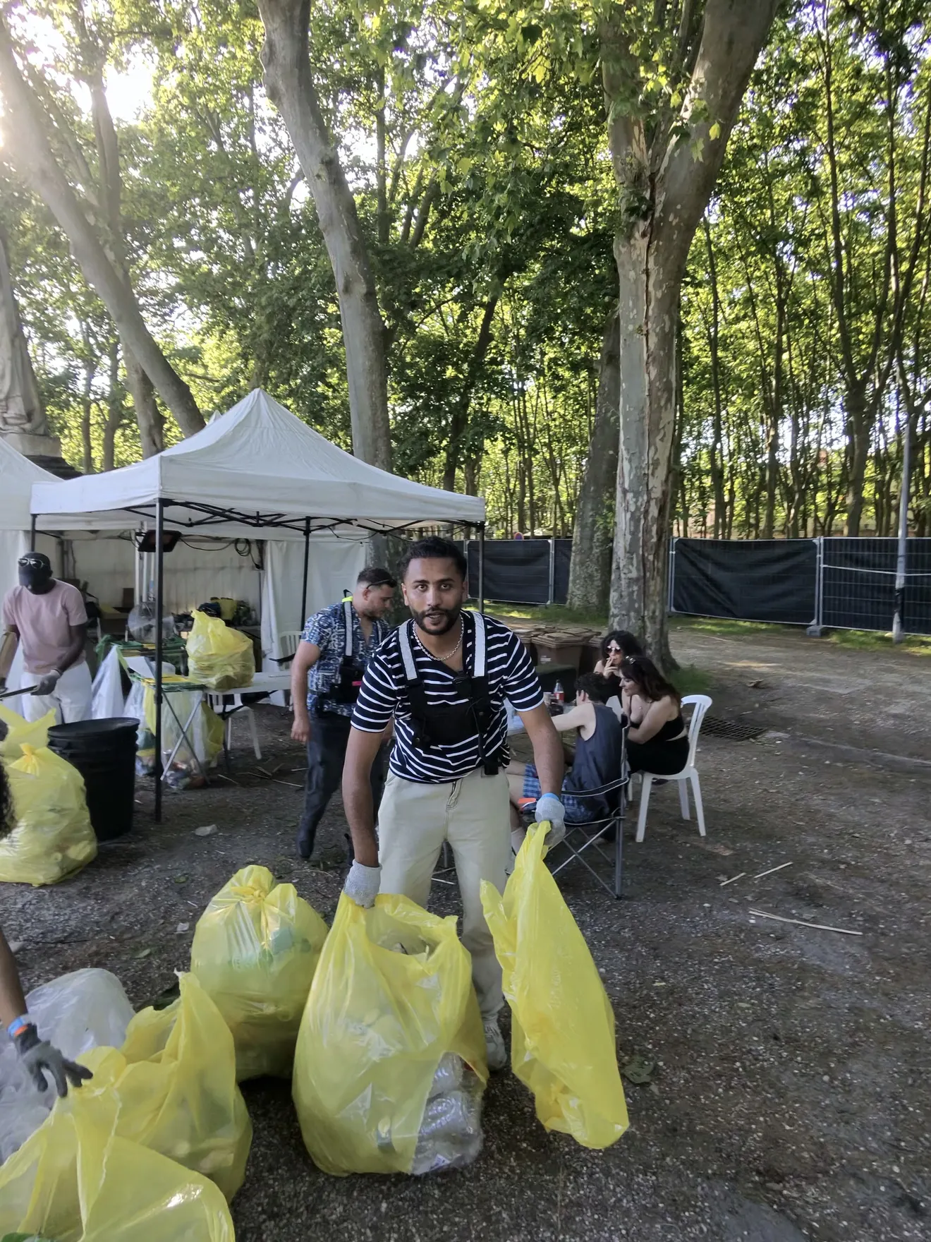 Un membre de la brigade porte les sacs de tri sur la zone logistique