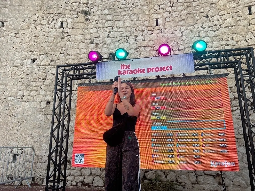 Une chanteuse sur scène devant l’écran et le mur de pierre de la Corniche