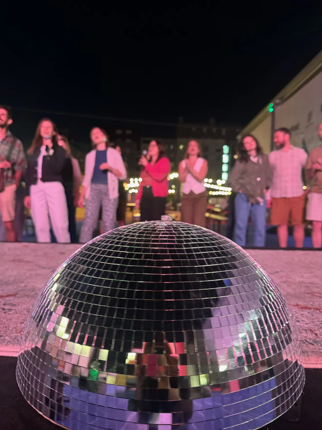 Le public chante derrière la boule à facettes de la scène au Vitamine 7